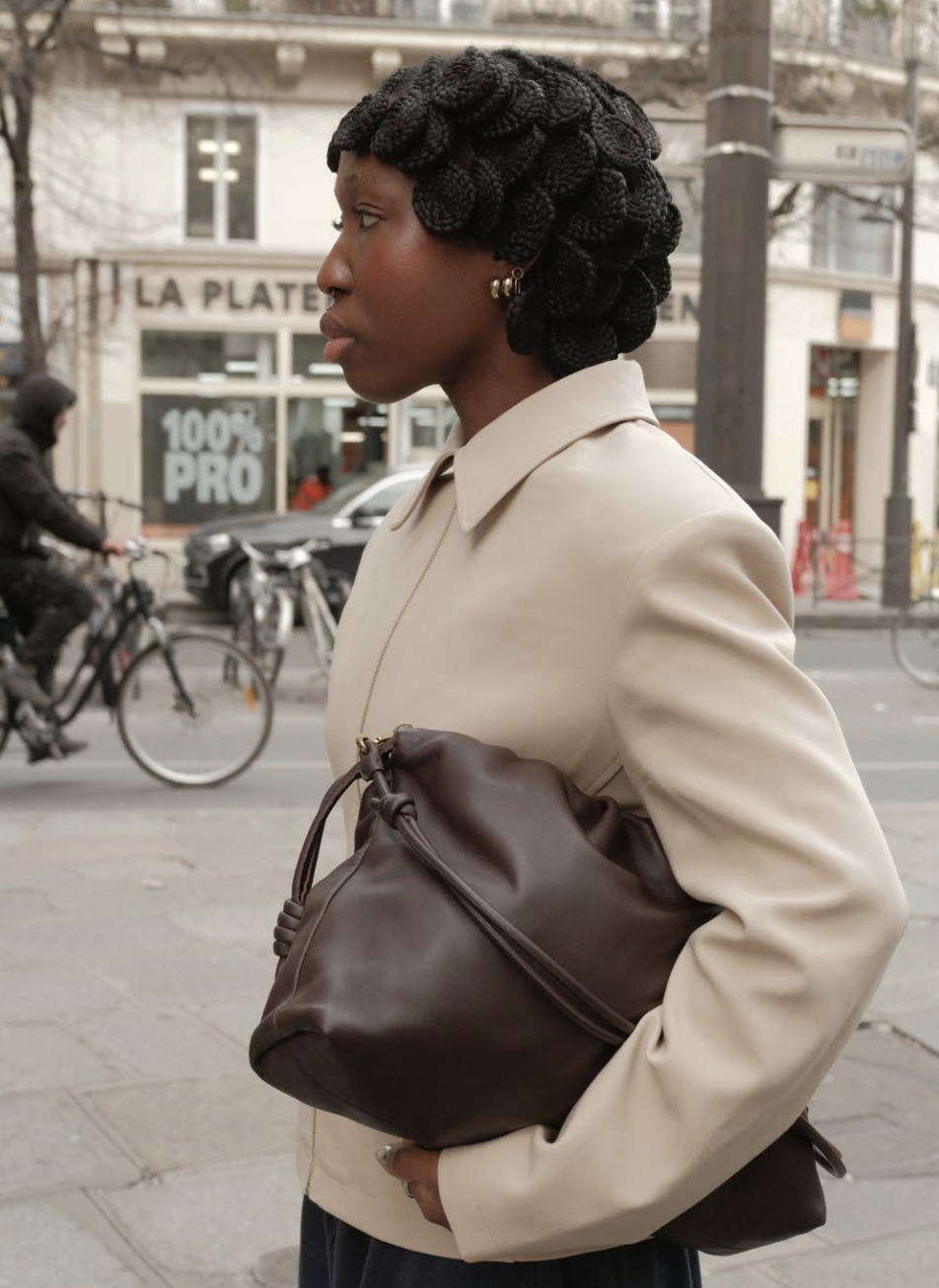 Close up of a woman wearing a tan coat and carrying a chocolate brown leather satchel bag, representing the poetcore aesthetic.