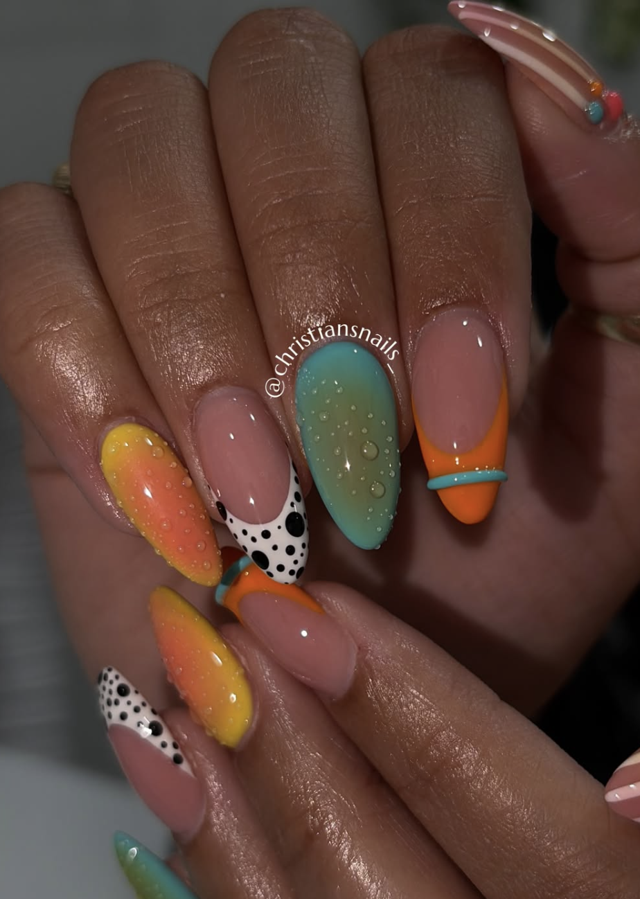 A close-up of long almond-shaped nails with a vibrant neon orange and yellow gradient French manicure, featured alongside a teal and black polka-dot accent nail textured with realistic 3D clear water droplets.