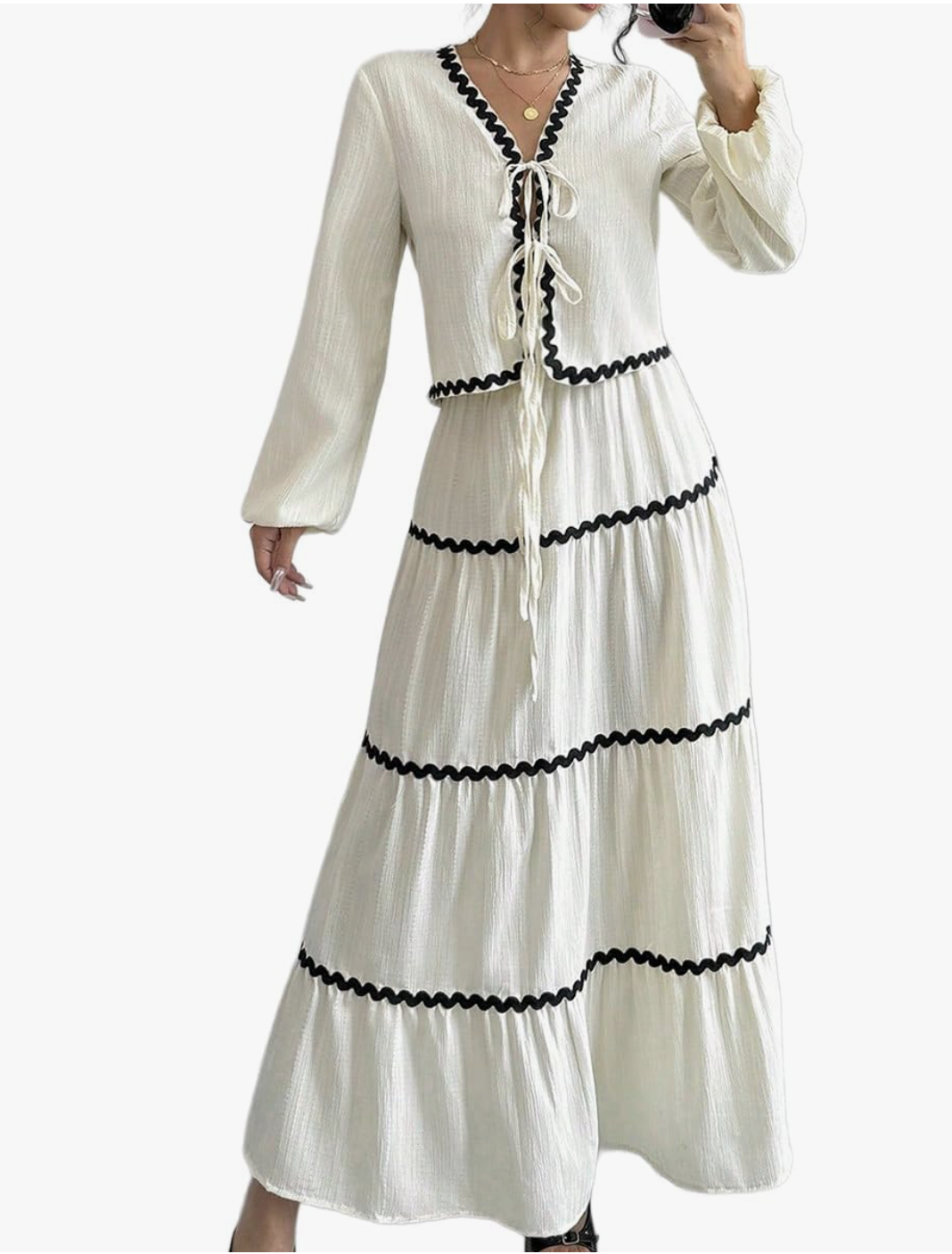 A woman wearing a cream and black long-sleeve cardigan and high-waisted maxi skirt set with contrasting trim.