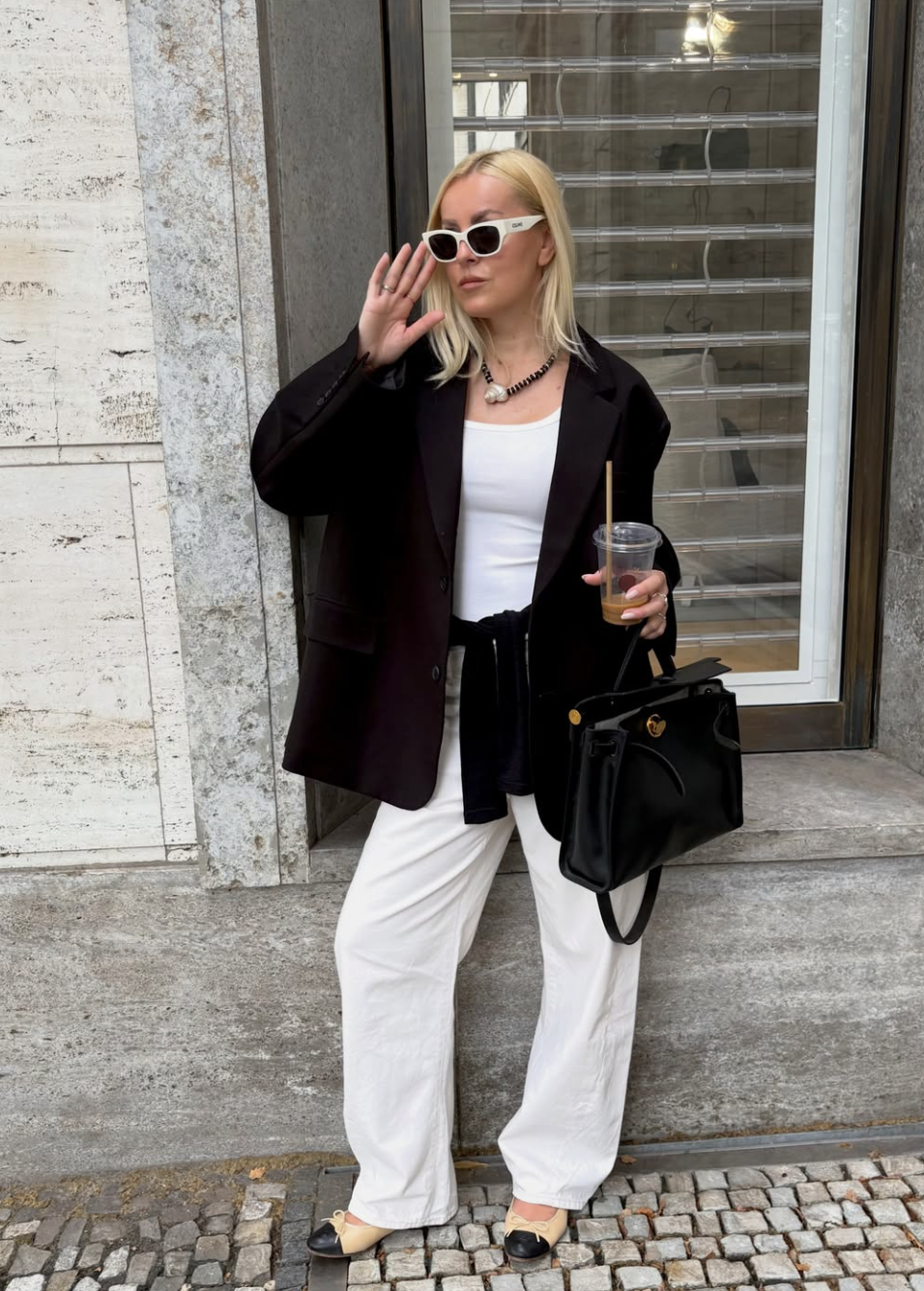 Oversized black blazer paired with relaxed white wide-leg trousers and a black shoulder bag.