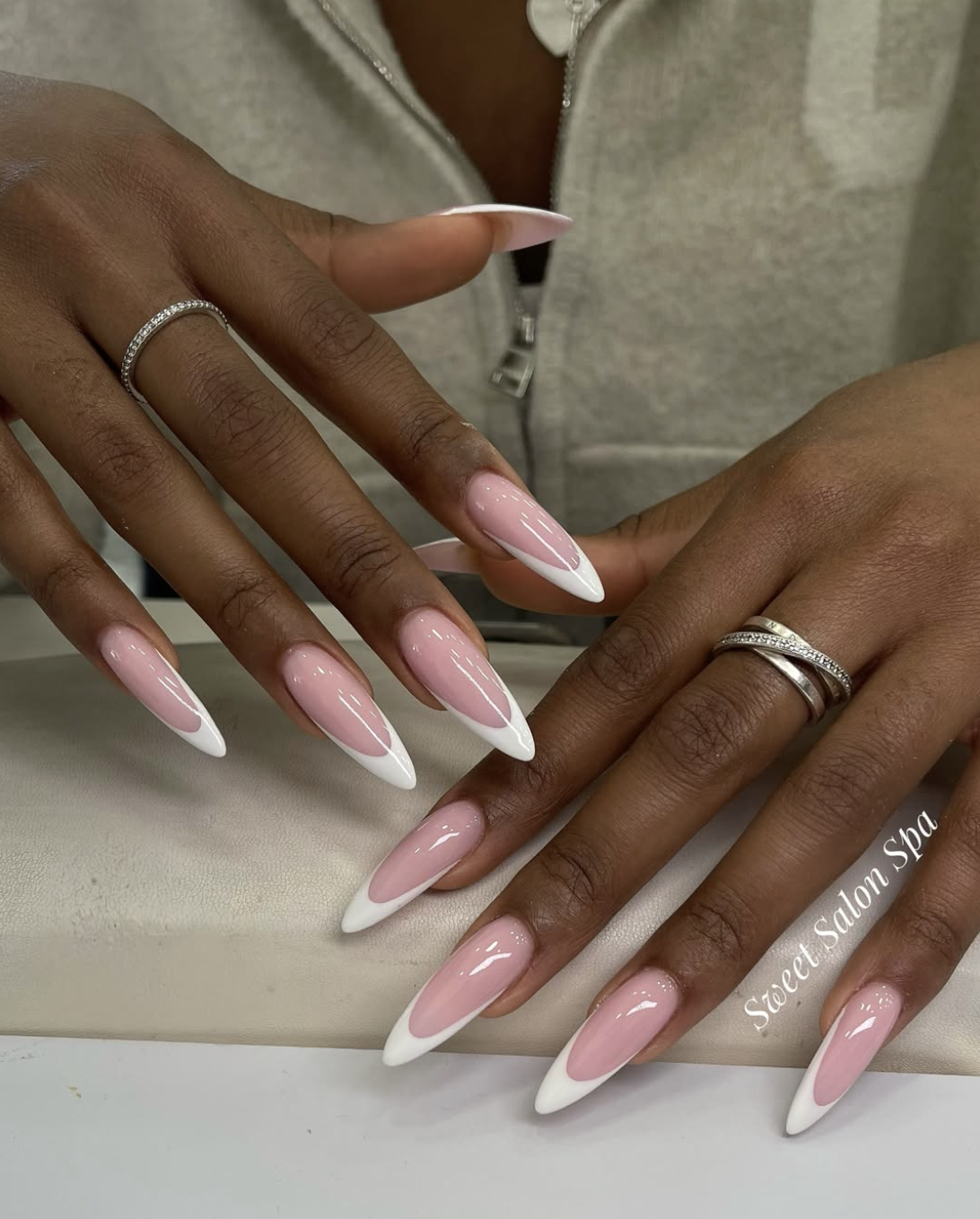 Extra-long almond shaped nails with a soft pink base and crisp white French tips.
