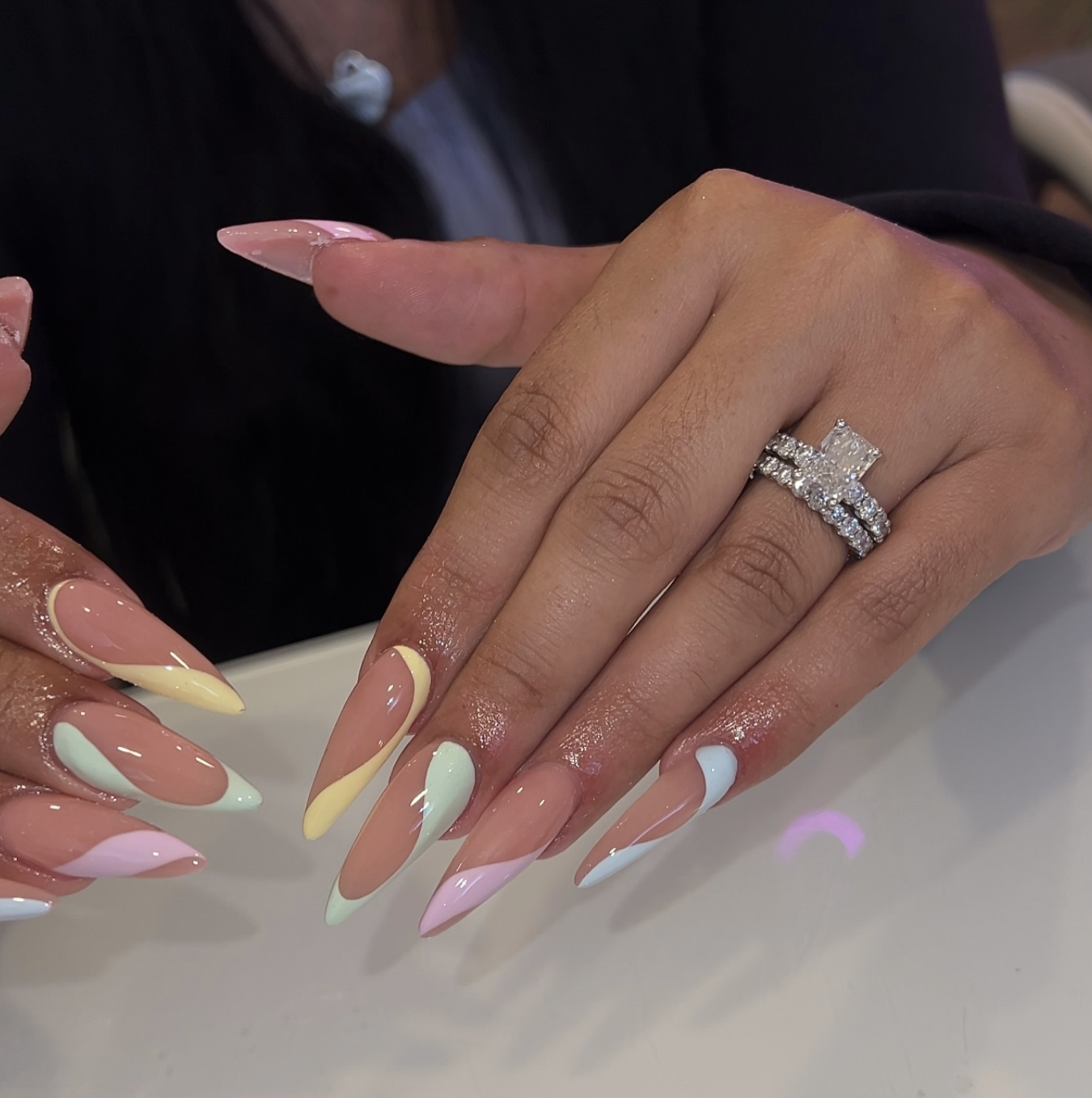 Long almond-shaped nails featuring a colorblock design with different pastel halves in mint, peach, and lavender.