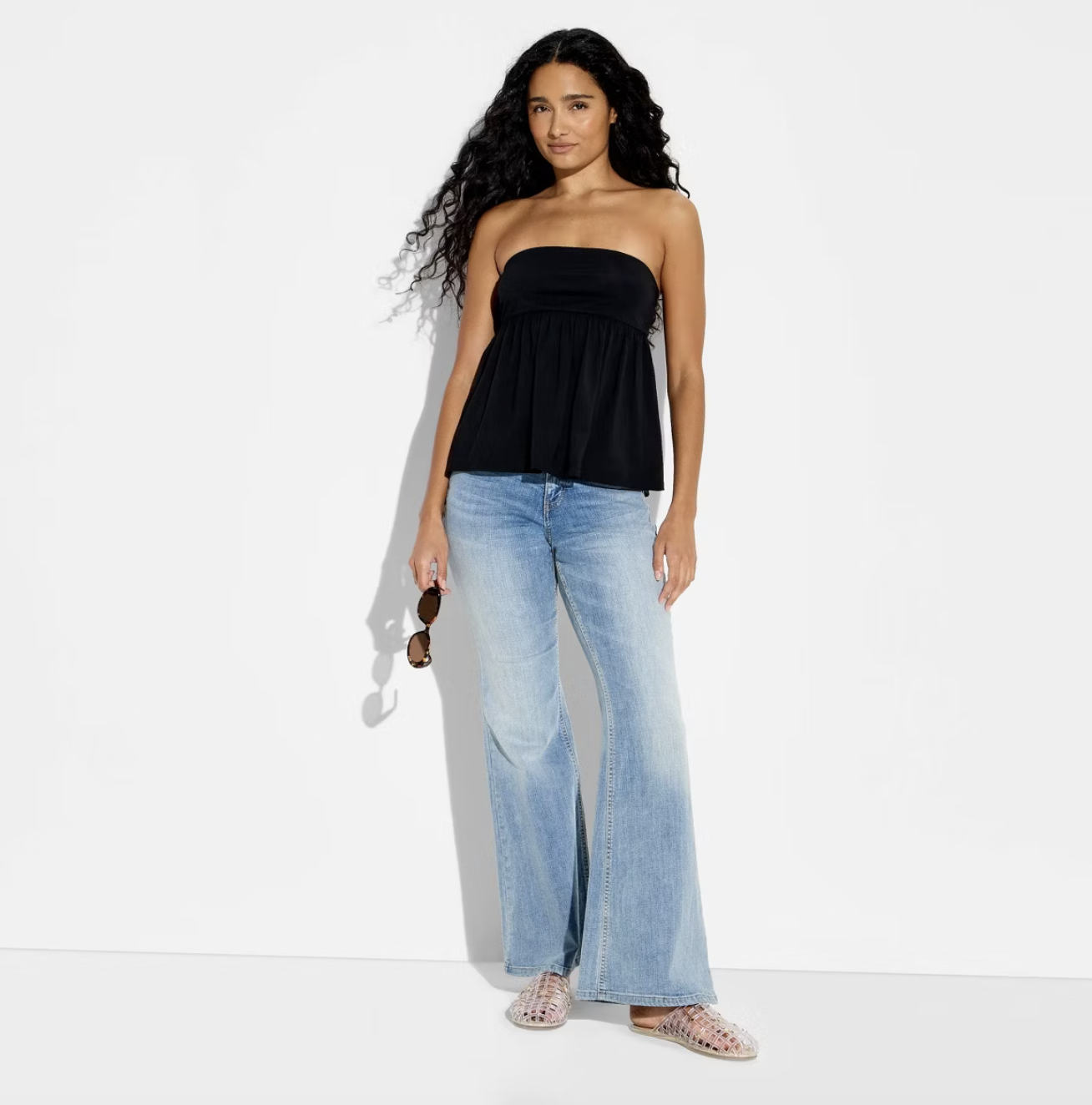 A woman wearing a black Wild Fable strapless babydoll tank top styled with light-wash wide-leg jeans for a casual Spring 2026 outfit.