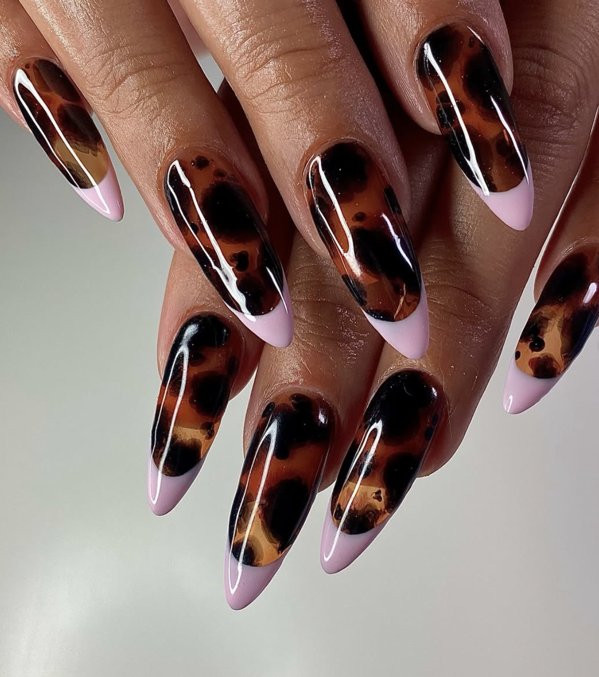 Tortoiseshell French tips with amber and dark-brown details on a sheer base.