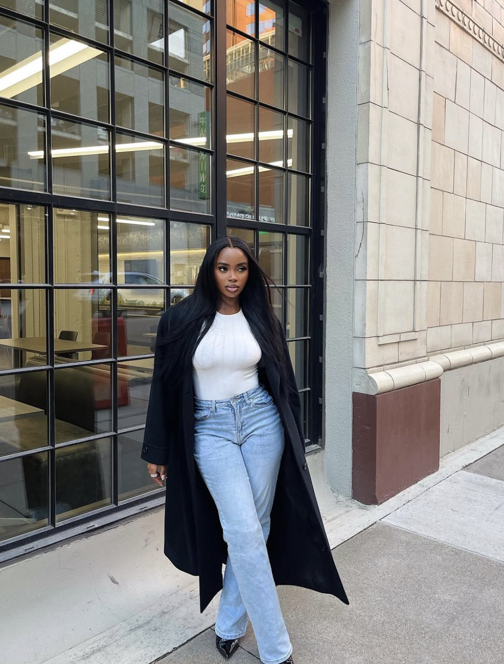 A fashion editor-inspired outfit featuring a simple white t-shirt tucked into high-waisted, light-wash straight-leg jeans, accessorized with a black leather belt and gold jewelry.