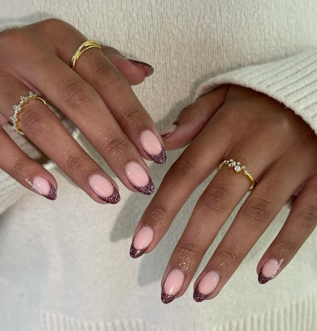 Almond-shaped nails with a sheer pink base and a sparkling dark purple and silver glitter gradient concentrated at the tips.