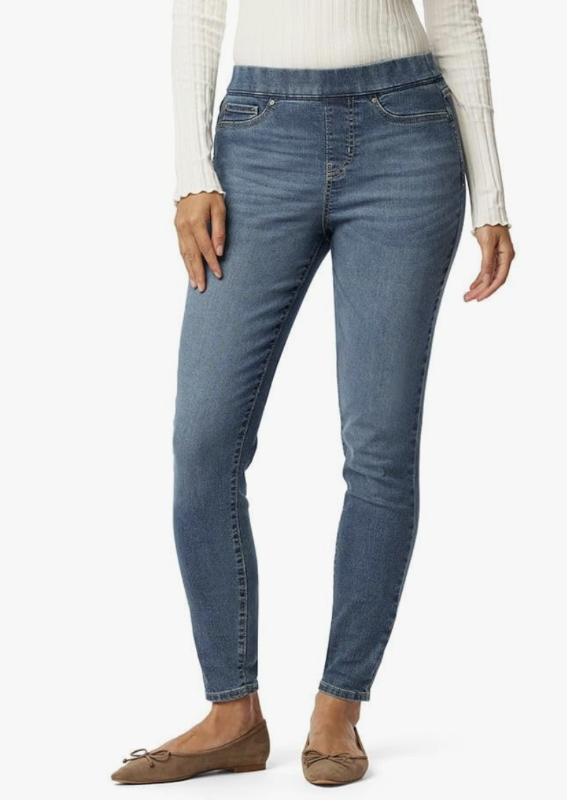 A close-up of high-waisted pull-on skinny jeans in a medium wash, styled with a white ribbed top to show the smooth, zipper-less waistband.