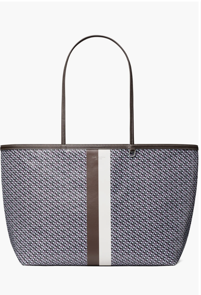 Patterned canvas tote bag in navy, white, and burgundy featuring a vertical brown leather stripe and brown top handles on a white background.