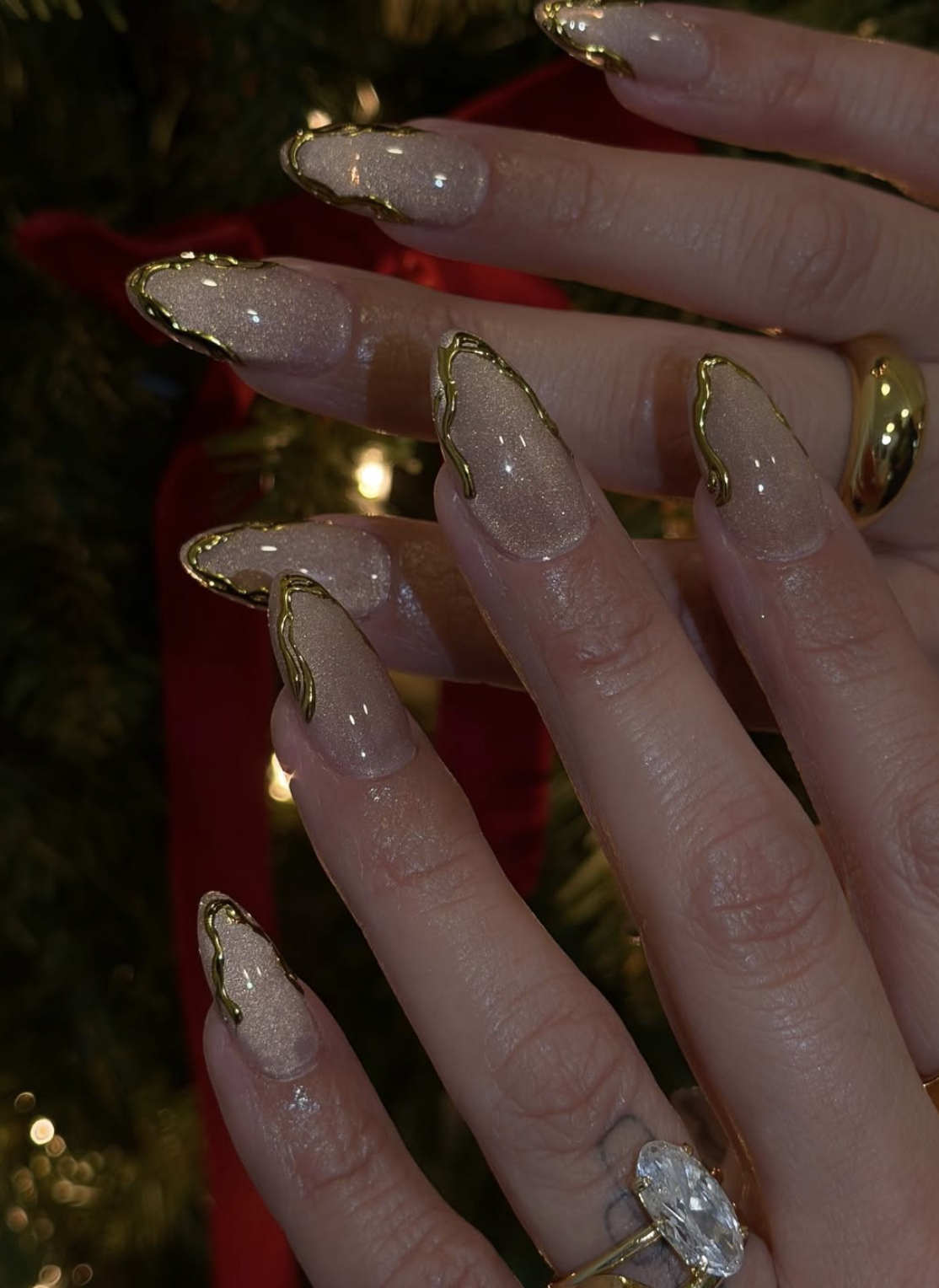 Gold chrome French tip Christmas nails over a sheer nude base