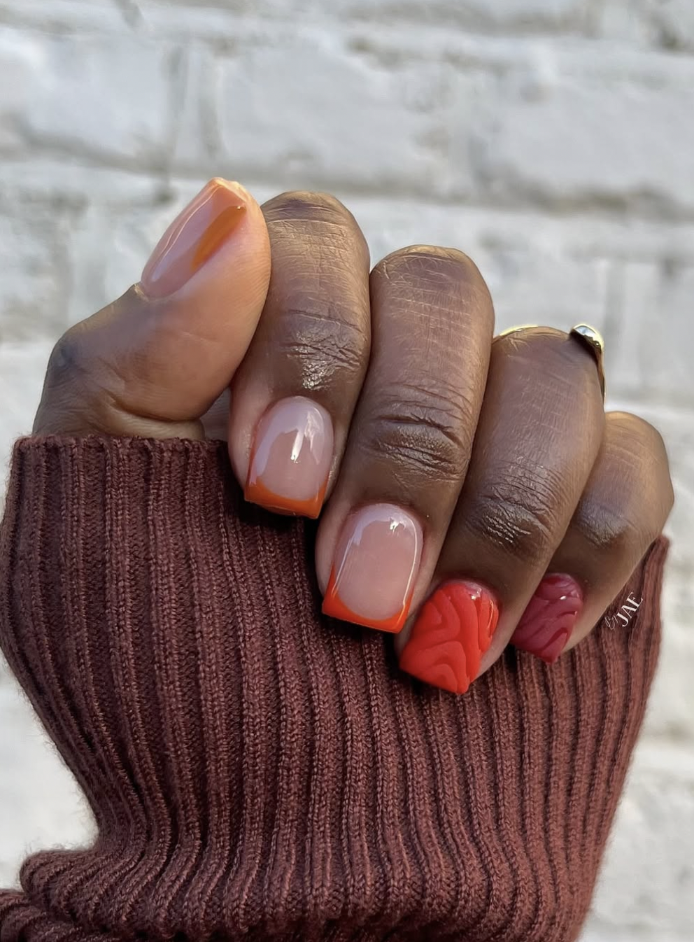 Short rounded nails painted a warm terracotta clay shade.