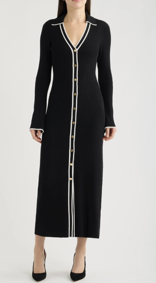 Woman wearing a black long-sleeve ribbed knit midi dress with white contrast trim and gold buttons down the front.