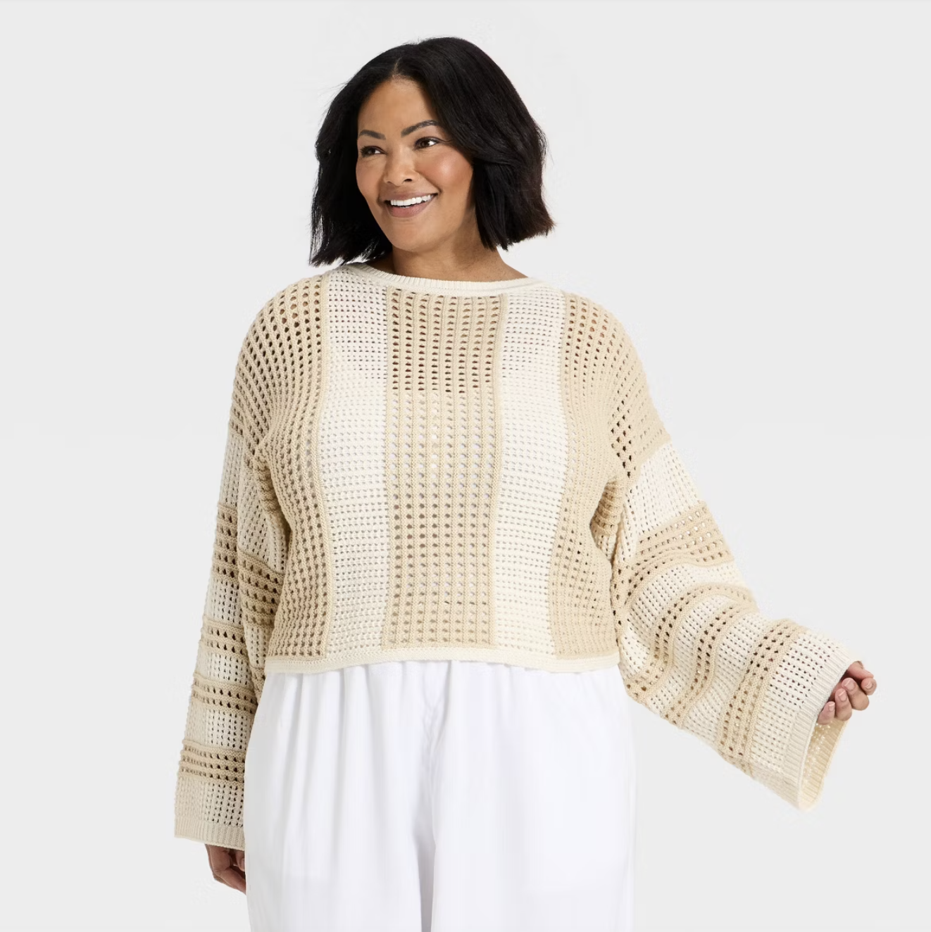 A woman wearing a cream A New Day oversized open-work knit pullover sweater, styled over a white top for a layered Spring 2026 outfit.