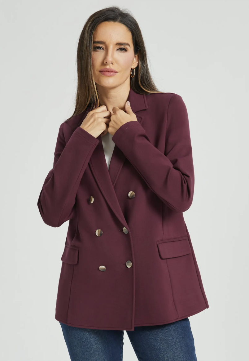 Front view of a woman wearing a burgundy double-breasted Betabrand blazer with gold buttons and a structured fit.