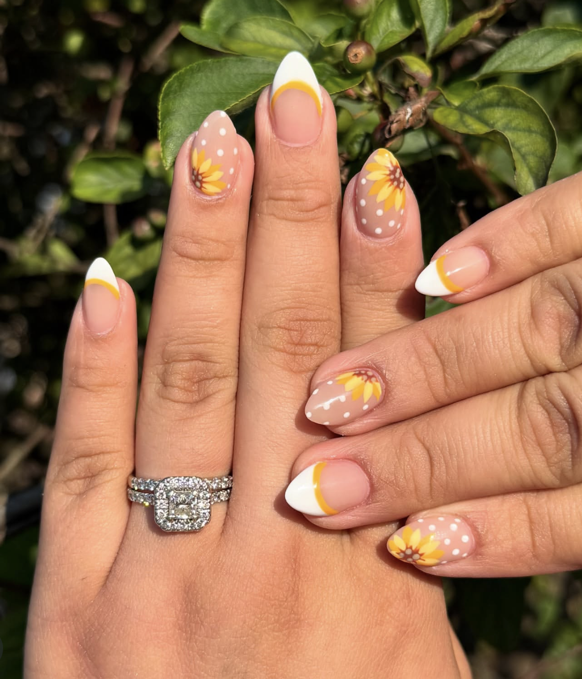 Almond-shaped nails with a white base featuring hand-painted yellow sunflowers with brown centers.