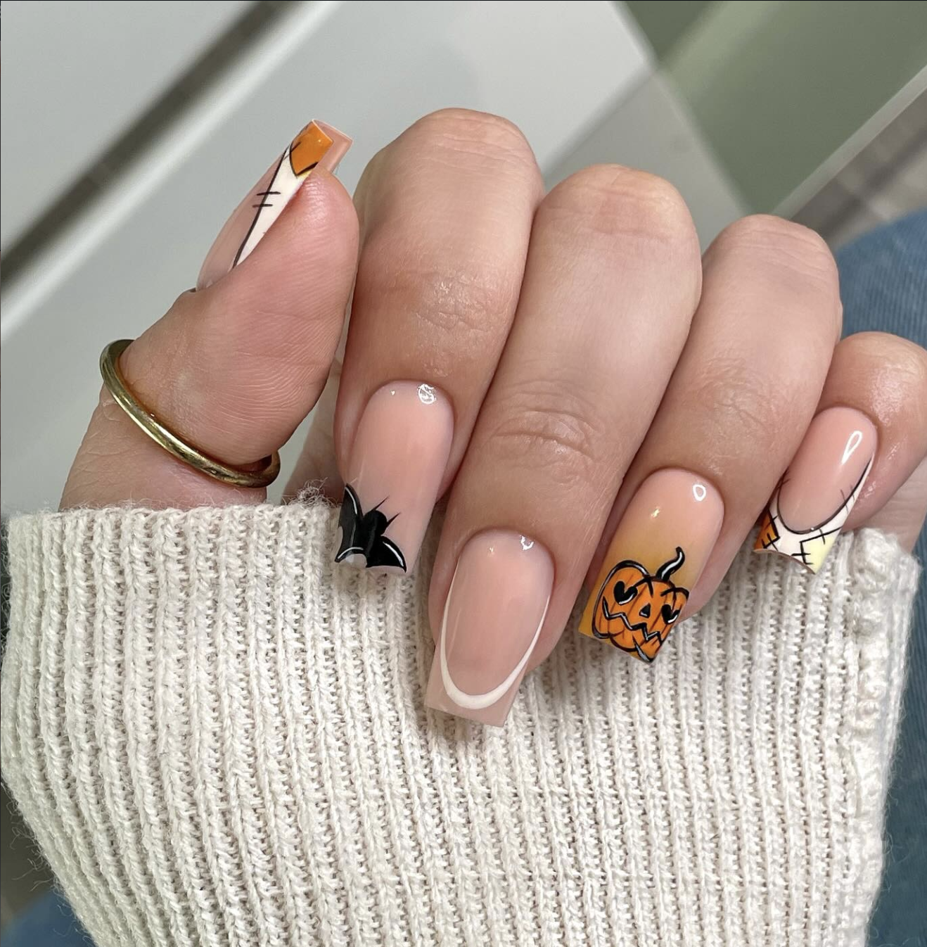 Orange French tips decorated with miniature jack-o-lantern faces