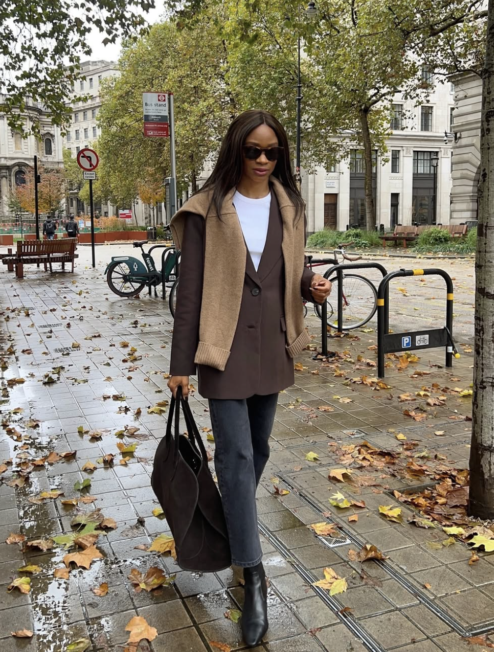 A woman wearing a tan faux suede blazer over a white top and blue jeans, demonstrating an elevated "High-Low" outfit formula for everyday wear.