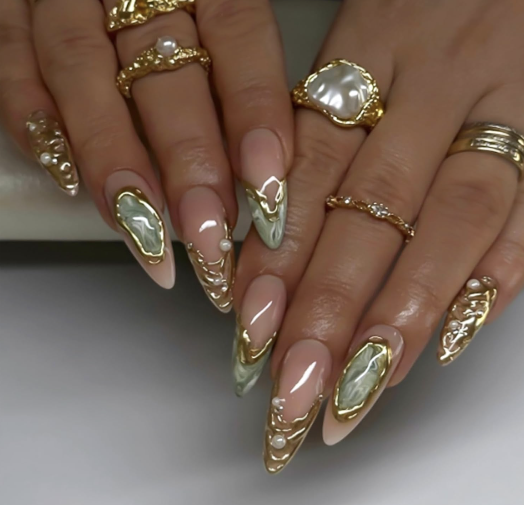 Medium almond-shaped press-on nails with a nude-to-pink gradient base, featuring gold glitter accents and a delicate gold 3D angel charm.