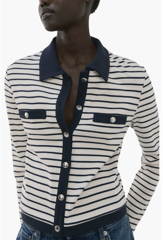 A woman wearing a navy and white striped fine-gauge knit polo cardigan with silver buttons styled with blue denim jeans.
