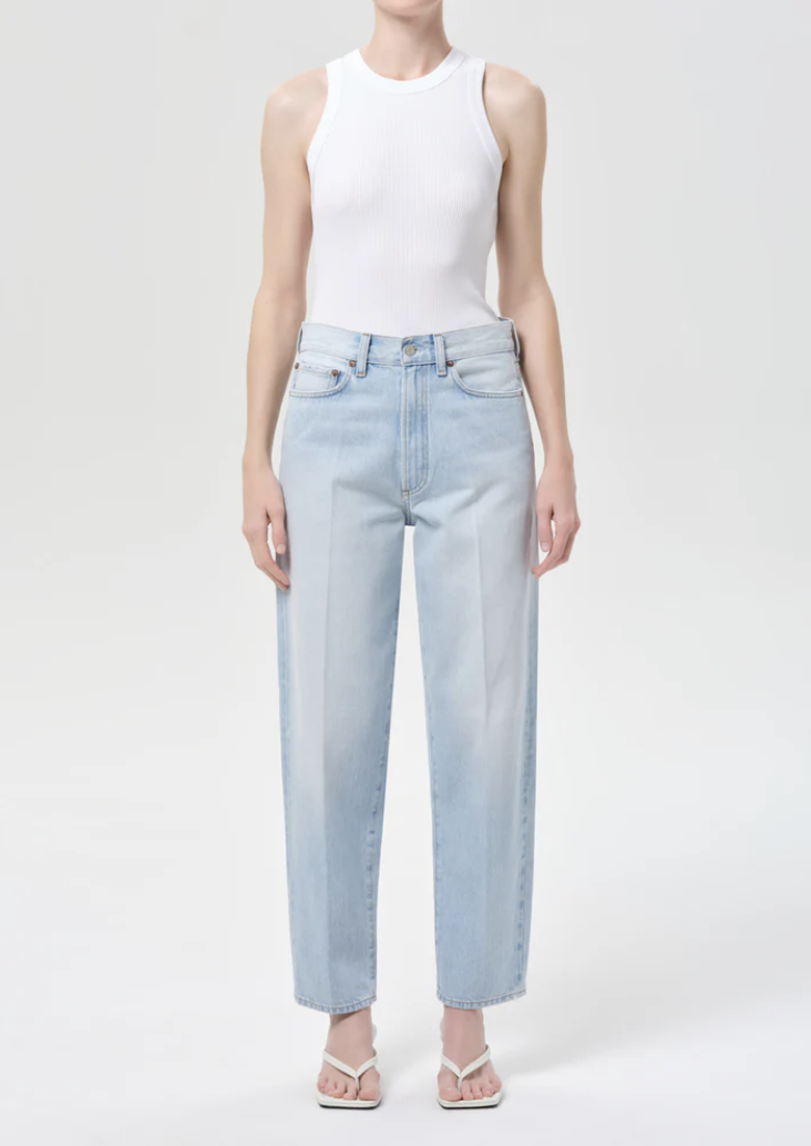 Front view of light wash cigarette jeans paired with white thong sandals.