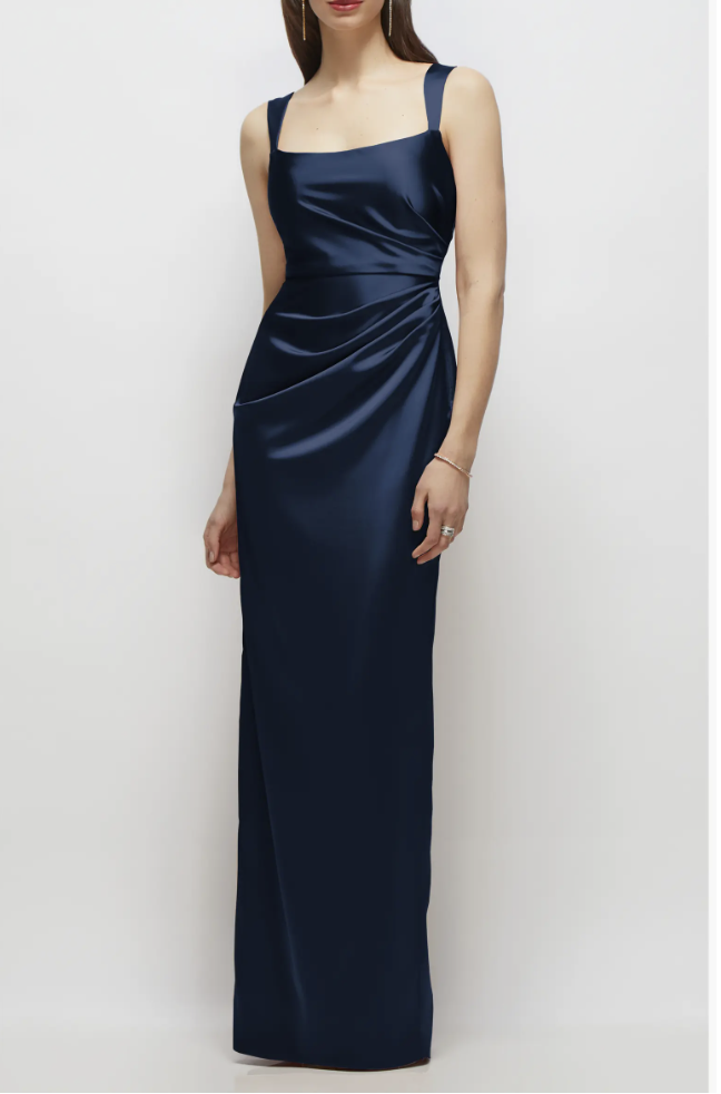 A woman wearing a floor-length, elegant navy blue satin gown with a structured cowl neck bodice and a beautifully draped, sleek column skirt.
