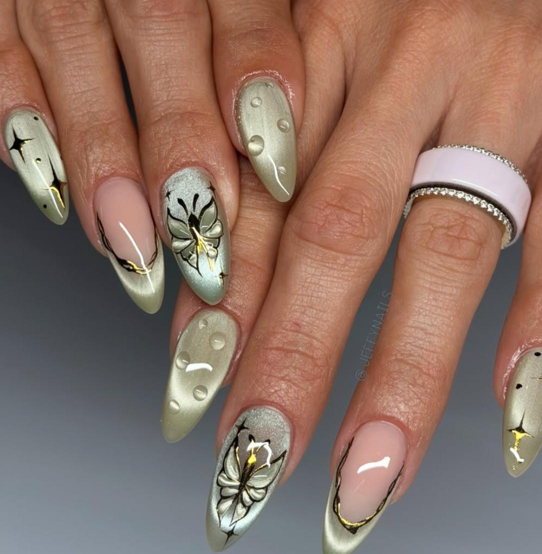 Long almond-shaped nails with a sheer seafoam green base, 3D gold chrome accents, and delicate white floral designs.