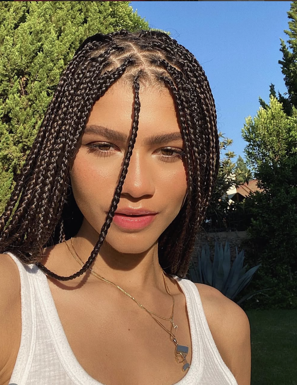 Zendaya wearing medium-length knotless braids with a middle part to frame an oval face shape.