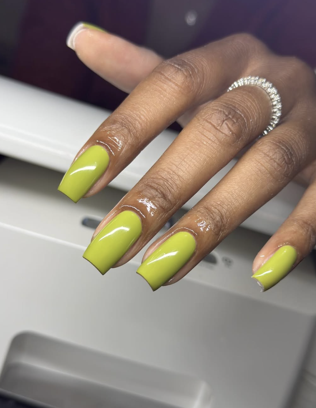 Short oval nails with muted glossy olive-green polish.
