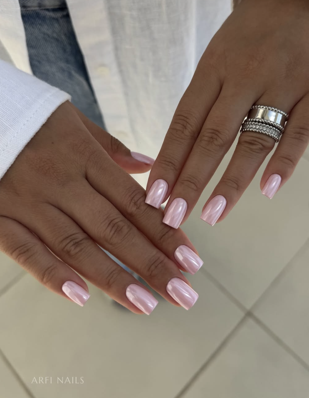 A close-up of medium-length square nails featuring a solid, high-gloss light pink chrome finish.