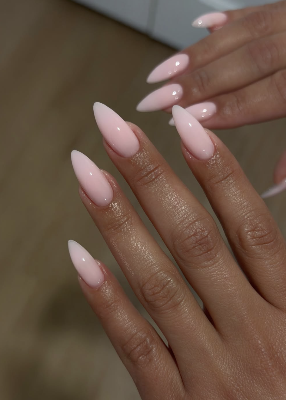 Medium almond shaped nails with a sheer pink soap nail polish and a high-shine, glassy finish.