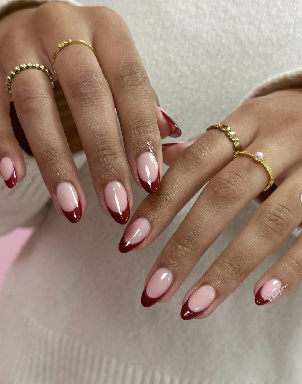Almond-shaped gel nails with a sheer nude base and deep, glossy cherry red French tips.