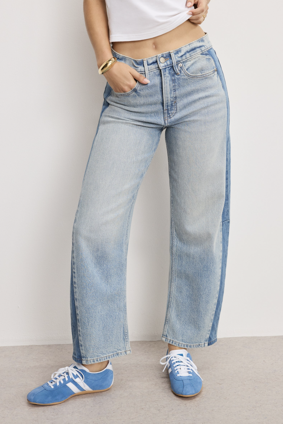 Light-wash high-waisted barrel-leg jeans styled with blue sneakers.