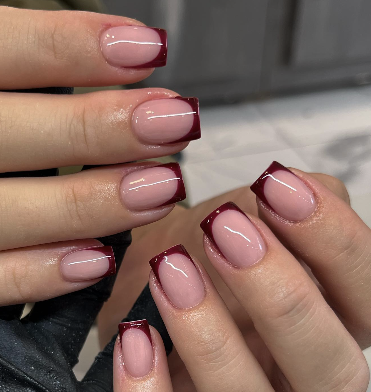 Close-up of oxblood micro french on neatly manicured hands