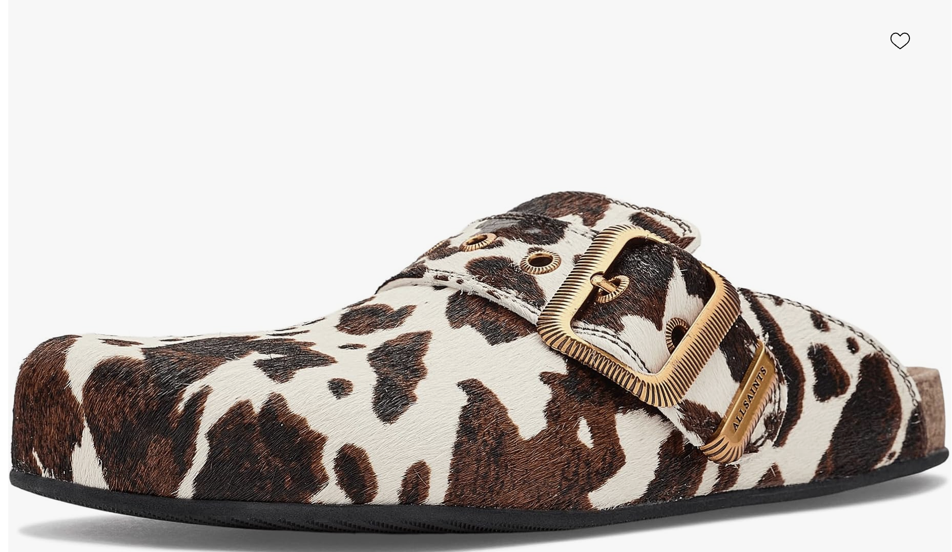 A close-up of an AllSaints Staffa mule shoe featuring a brown and white cow-print pony hair finish with gold buckle details, styled to wear with white jeans.