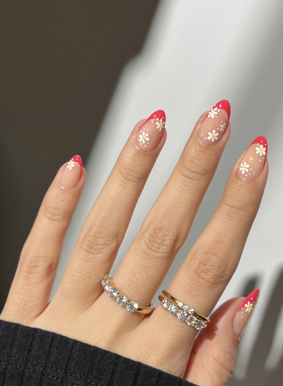 Almond-shaped French tip nails with hand-painted red and white poppy flowers on the tips.