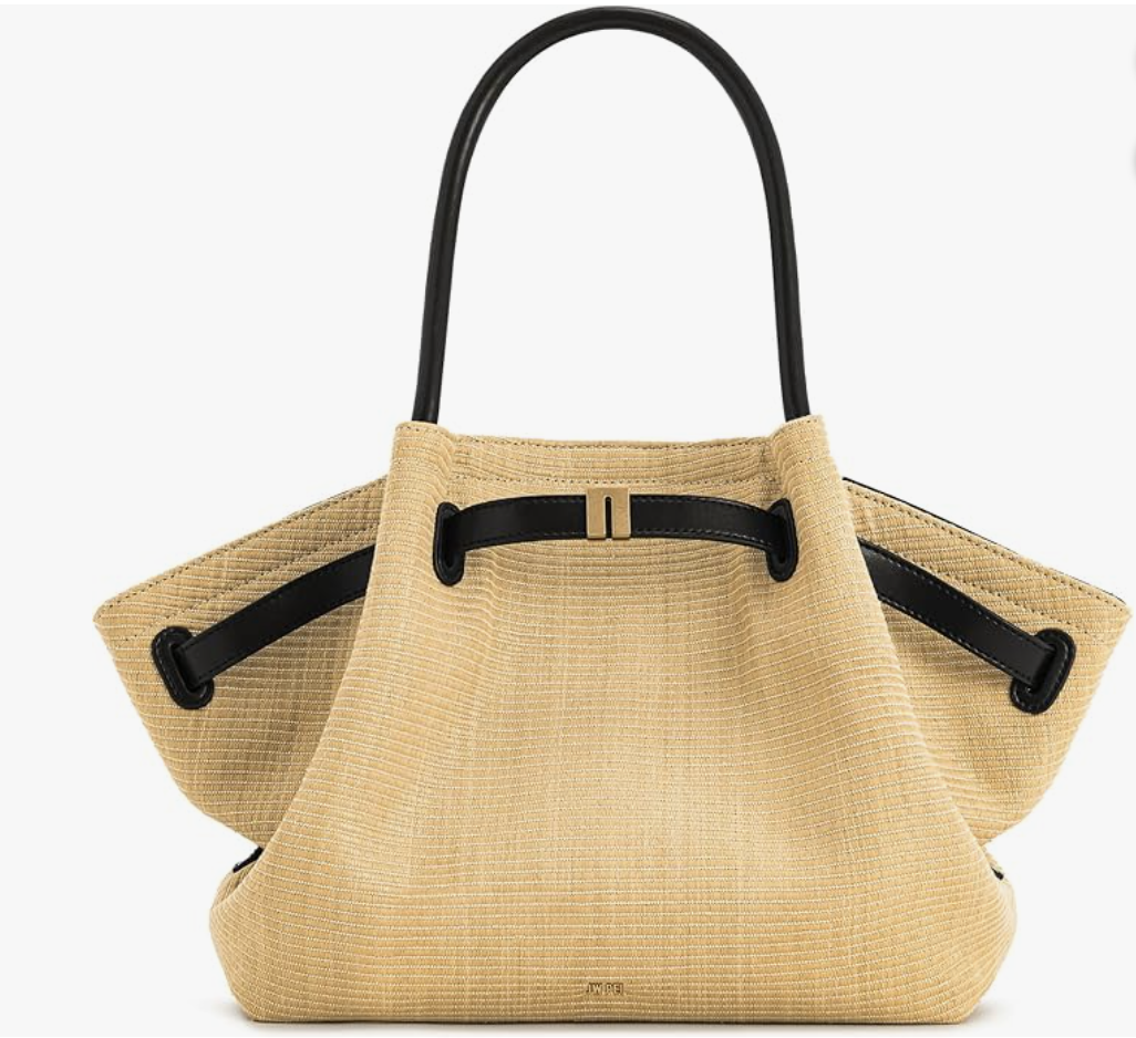Front view of a JW PEI Hana medium tote bag made from woven straw fabric, featuring a structural flared shape, black leather top handles, and a decorative black leather front strap with gold metal hardware.