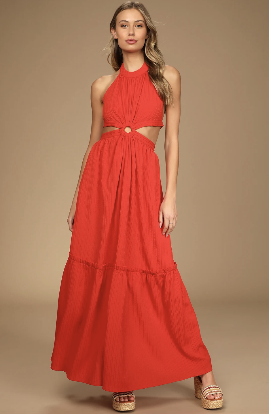 Front view of a vibrant red maxi dress from Lulus, featuring a halter neckline, a structured O-ring cutout detail at the waist, and a flowing, tiered floor-length skirt.