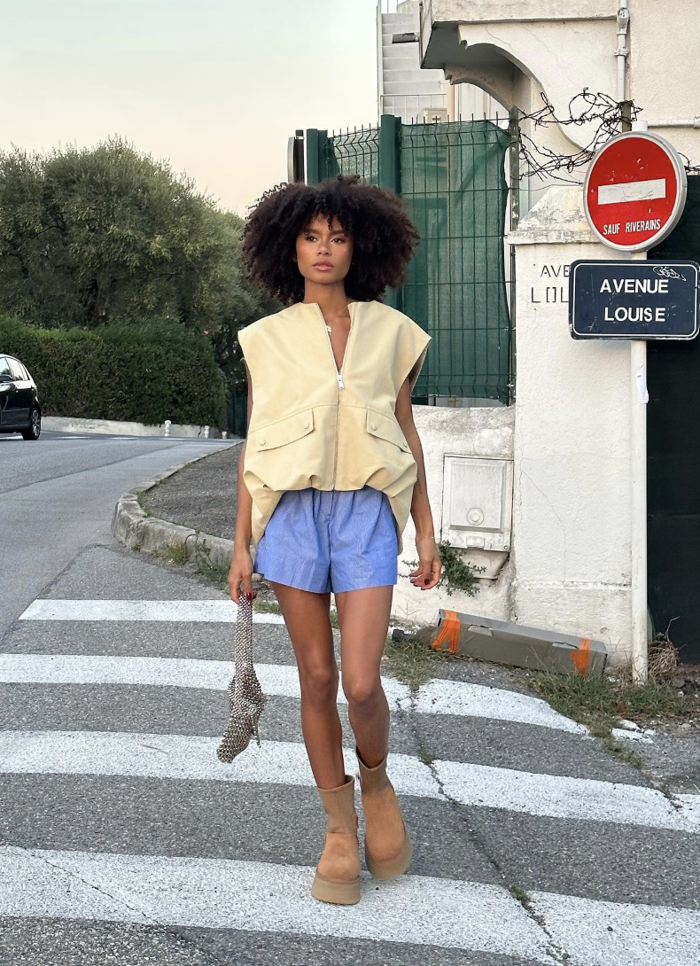 Pale-yellow buttoned vest and blue shorts with chestnut boots.