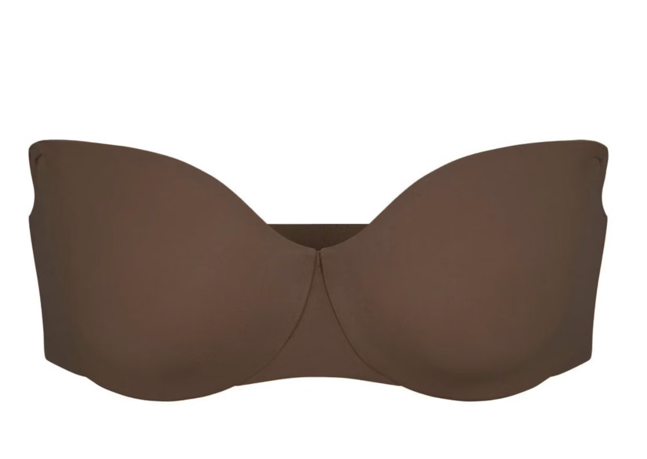 A brown Skims unlined strapless bra, shown as a supportive undergarment option for what to wear with a spaghetti strap dress.
