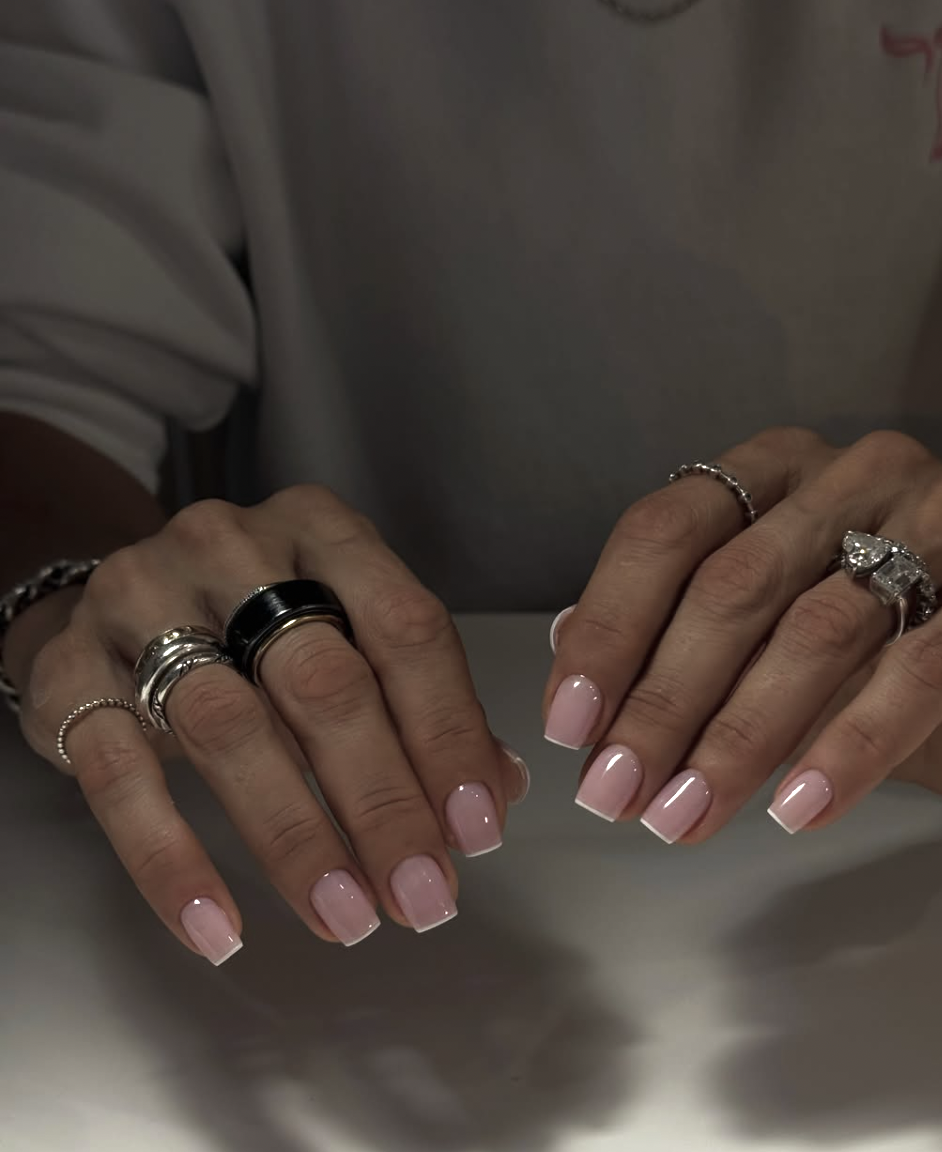 Long, square-shaped nails with a glossy, semi-sheer pink base coat and an ultra-thin, precise white French tip finish.