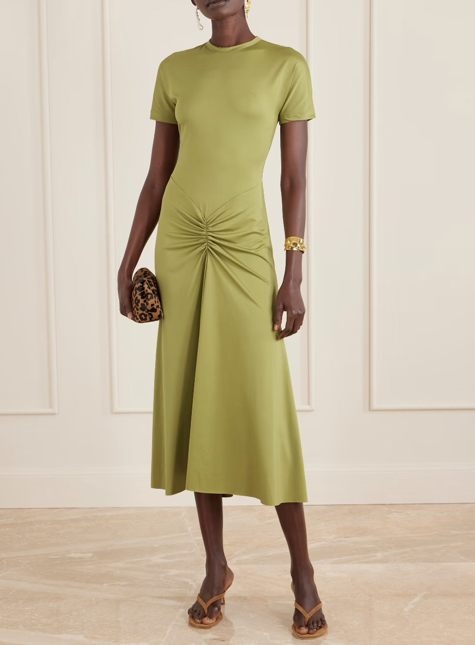 A woman wearing an olive green Victoria Beckham gathered satin-jersey midi dress, a sophisticated and architectural choice for a luxury spring wedding guest.
