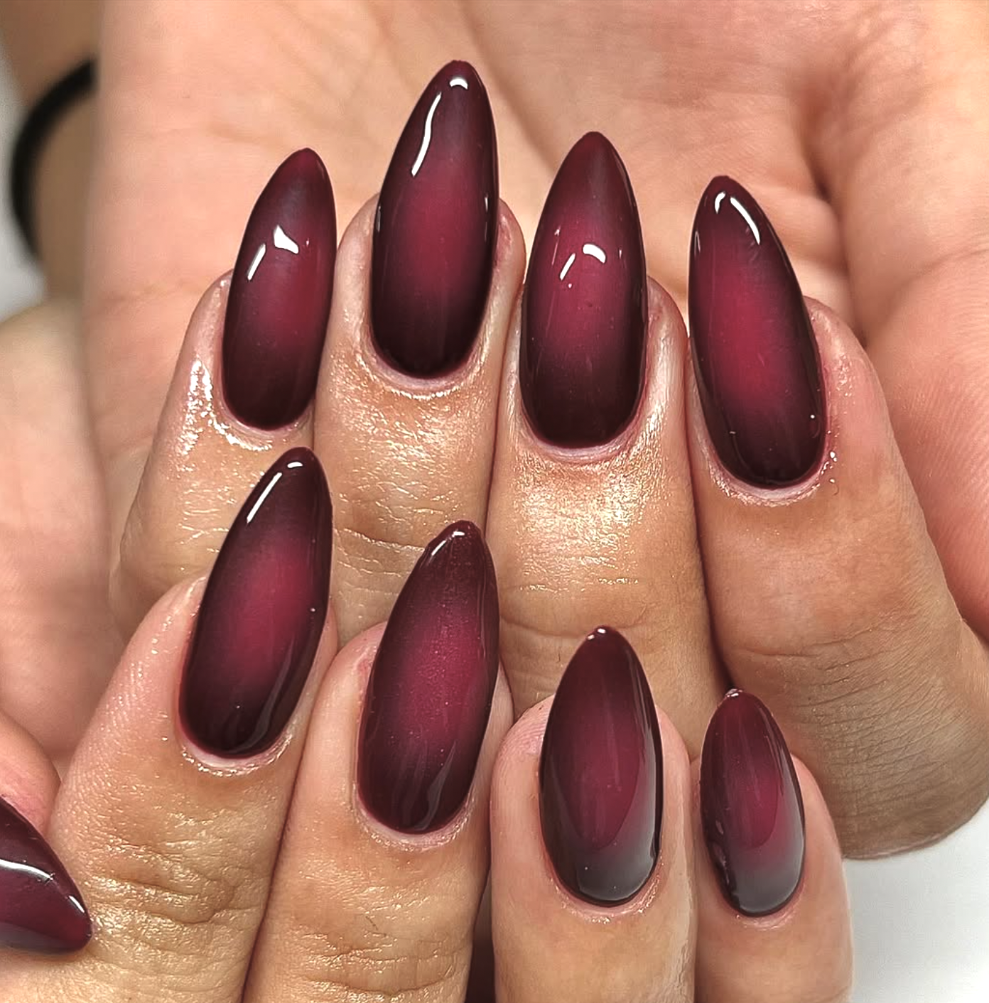 Glossy plum and black-cherry aura nails.