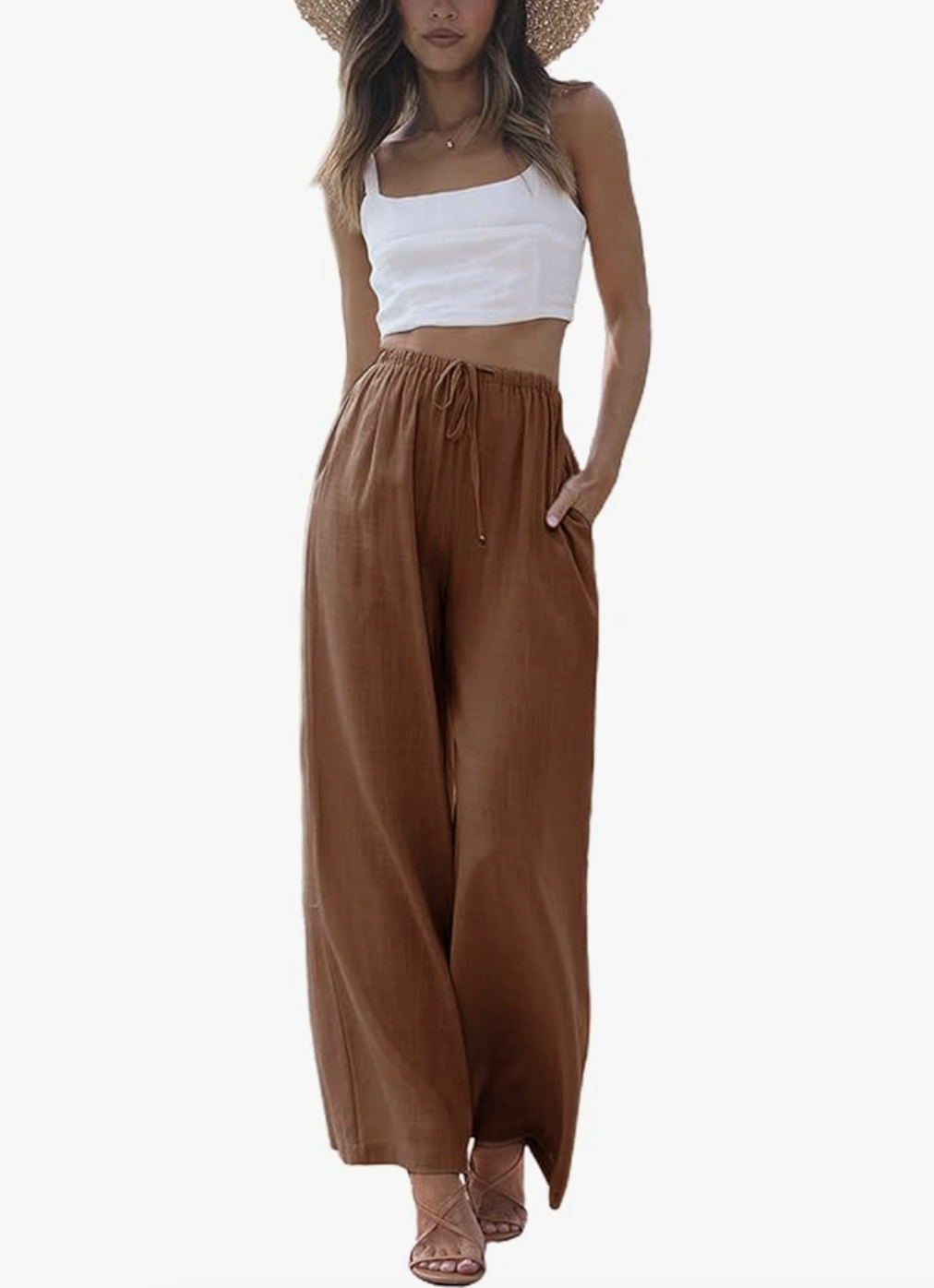 A woman wearing brown wide-leg cotton linen pants with a white crop top, styled as a breezy daytime outfit for what to wear on a cruise.