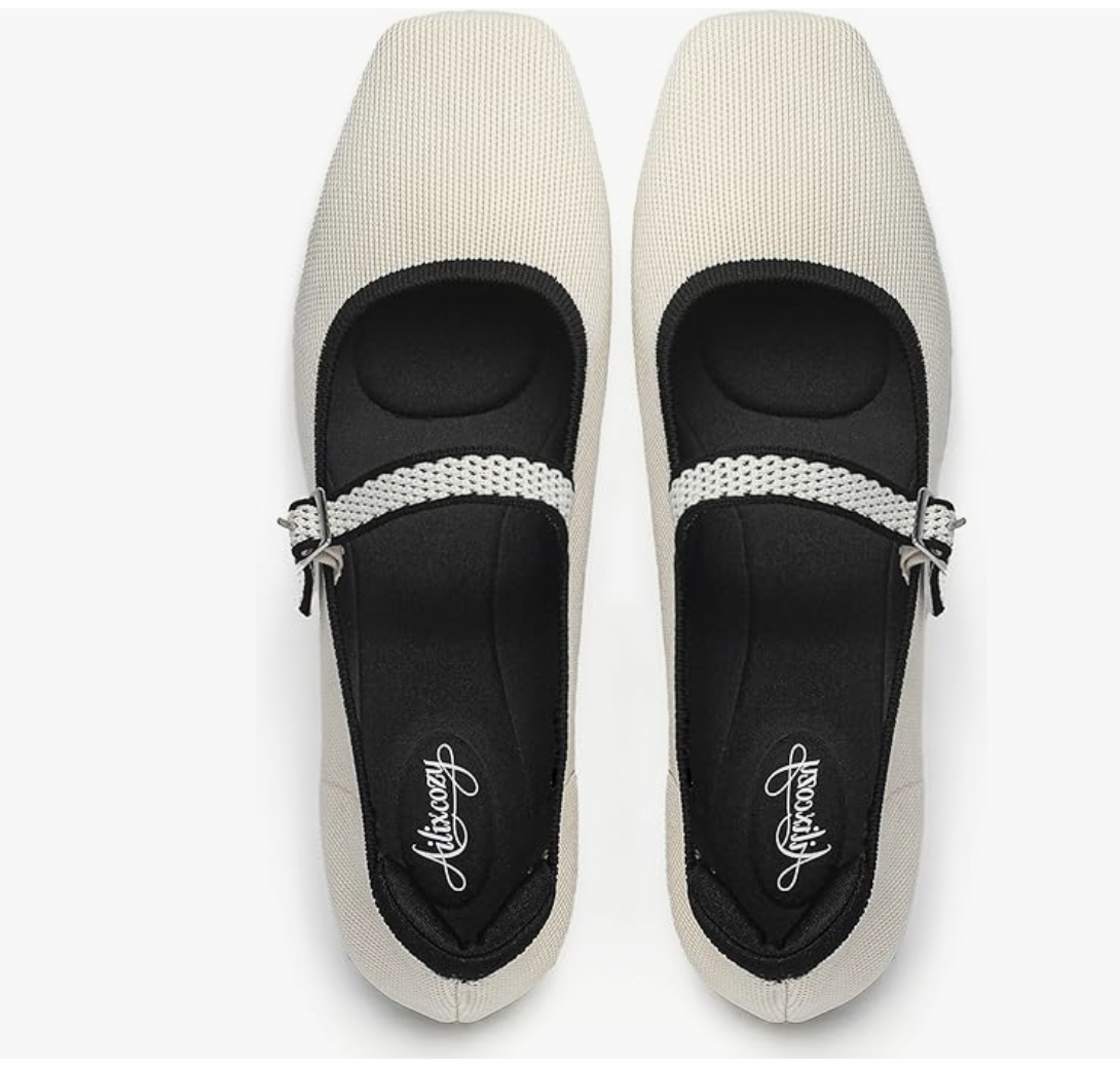 A pair of white knit Mary Jane flats with a black interior, featuring a woven strap with a decorative buckle, shown on a white background.