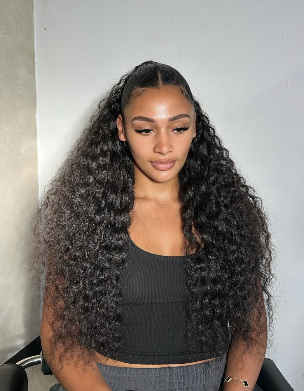 A woman with a square face shape wearing a half-up, half-down style with long, voluminous curls that add height and frame the jawline.