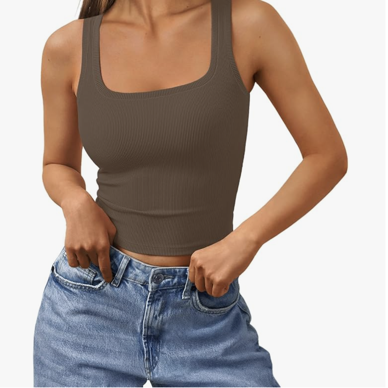 A close-up of a woman wearing a fitted, dark brown ribbed tank top with a square neckline, tucked into high-waisted light-wash denim jeans.