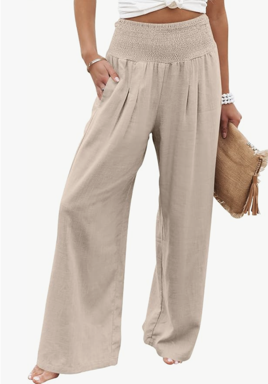 A close-up view of a casual summer outfit featuring high-waisted, wide-leg linen trousers in a neutral tan color with a smocked waistband and side pockets.