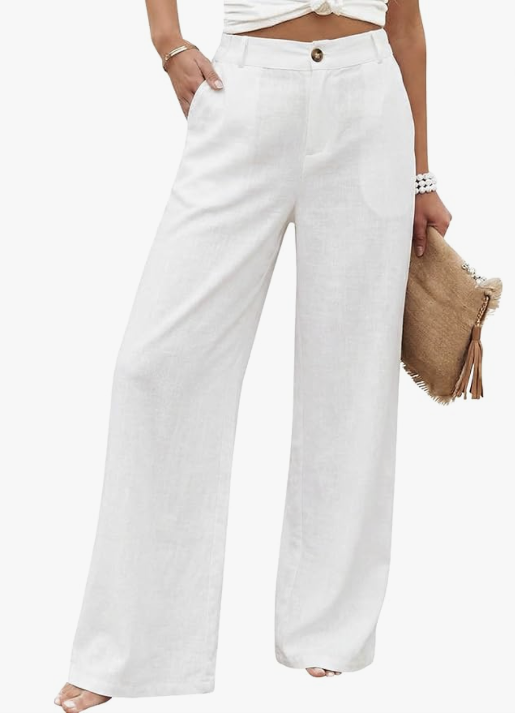 A close-up of a woman wearing breezy, high-waisted white wide-leg linen pants, paired with a brown woven leather clutch bag.