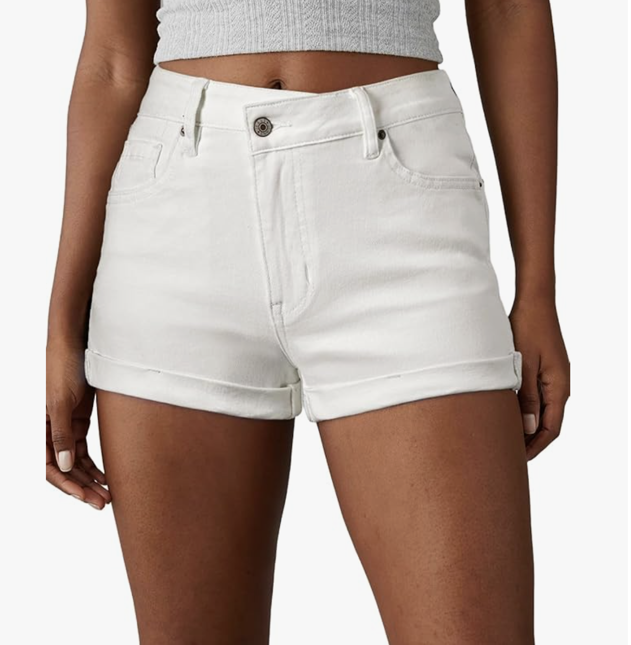 A close-up view of a woman wearing high-waisted, structured white denim shorts with a classic cuffed hem.