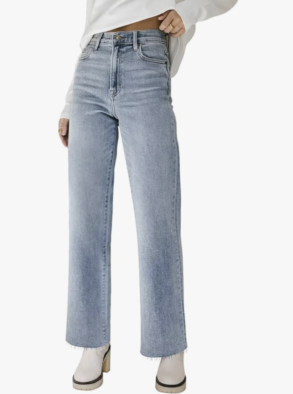 A woman in her 60s wearing light-wash straight-leg ankle jeans with a raw hem, styled with white heeled ankle boots for a modern spring capsule wardrobe.