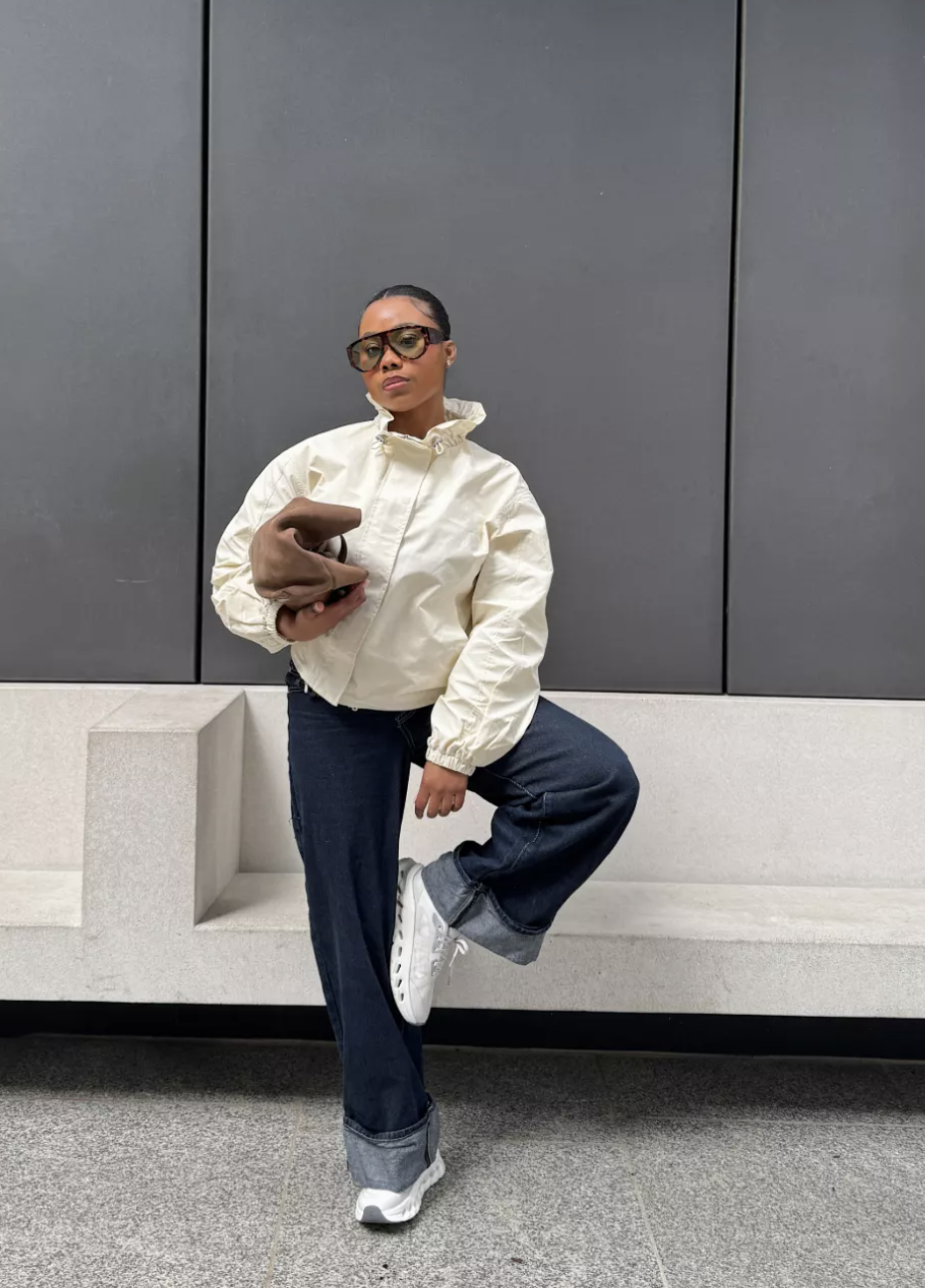 Person wearing chunky white retro runner sneakers with cuffed dark wash wide-leg jeans, showcasing a balanced proportion contrast for spring styling.